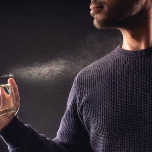 Man Spaying Perfume on Dark Background